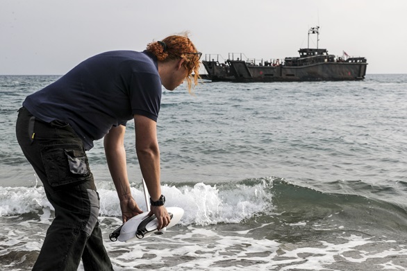 Scientist Natalie Anders launches a seabed-scanning device with a landing craft in the background