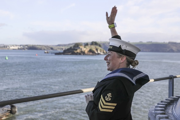 A female Leading Hand waves as HMS Albion enters Plymouth after 3 months away