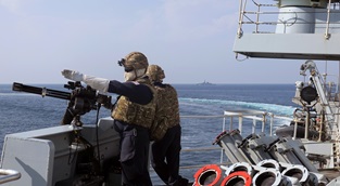 A Minigun operator on HMS Montrose keeps their eyes on the target